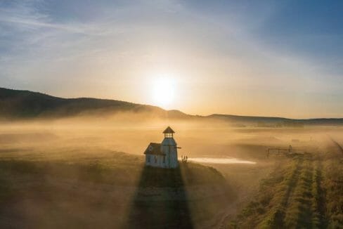 Klamath County Ranch Offering - Lighthouse Ranch 1 A picture of the sun rising against the backdrop of a lighthouse on a Klamath County ranch for sale.